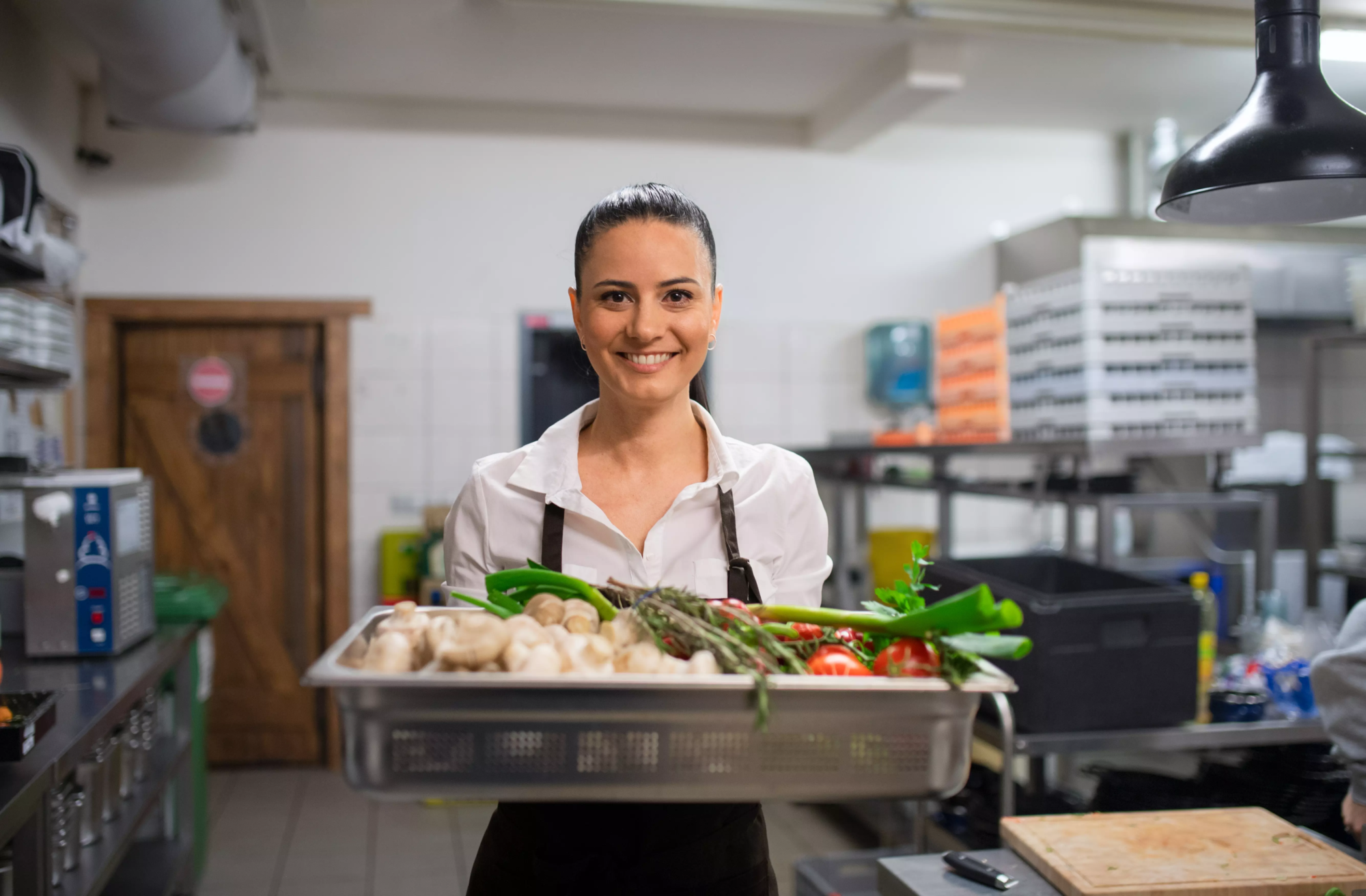 femme-chef portant un plateau avec des légumes frais